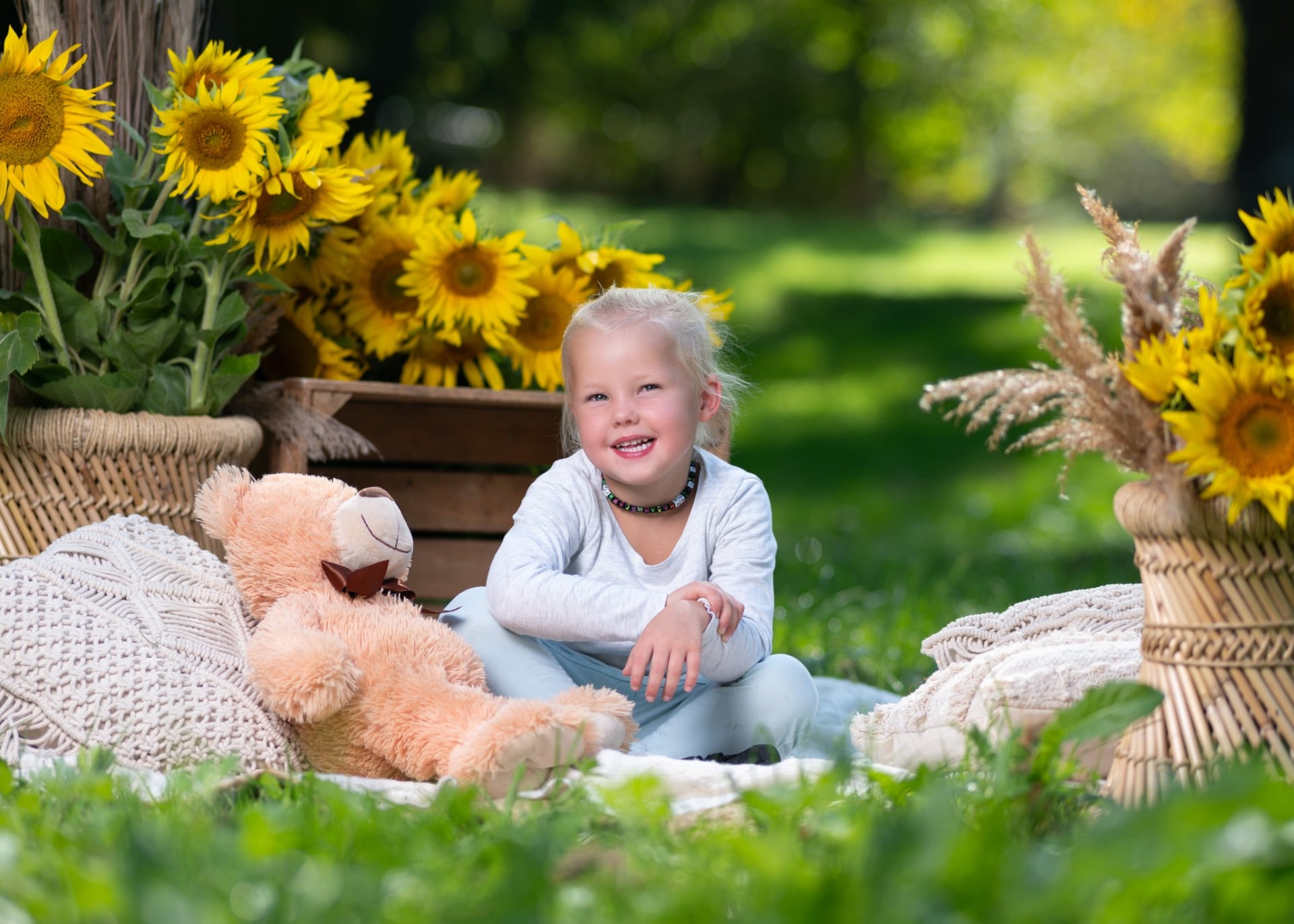 Kind lacht herzlich mit seinem Teddybären auf der Wiese
