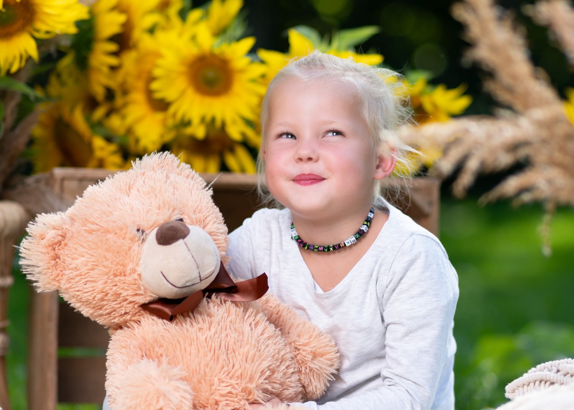 Kind mit Teddybär schaut verträumt nach oben